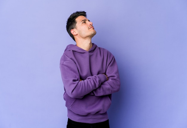 Young caucasian man isolated on purple dreaming of achieving goals and purposes