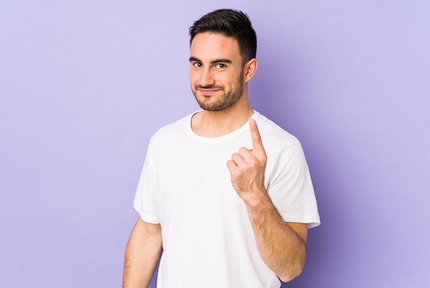 Young caucasian man isolated on purple pointing with finger at you as if inviting come closer.