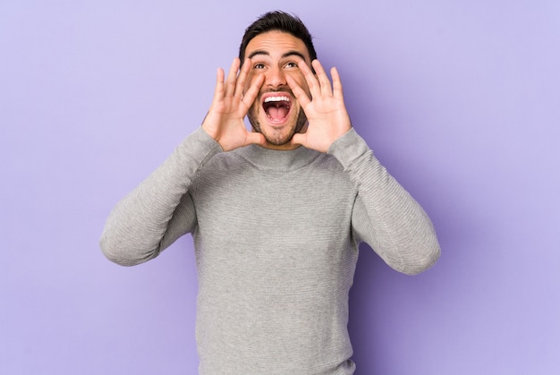 Young caucasian man isolated on purple shouting excited to front.