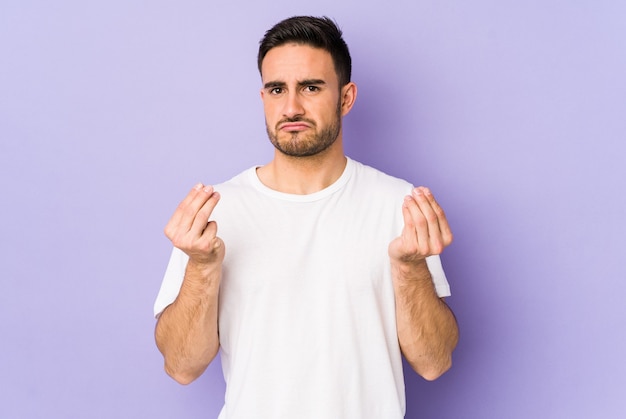 Young caucasian man isolated on purple wall showing that she has no money.