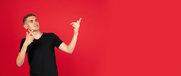 Young Caucasian man isolated over red studio surface in neon light