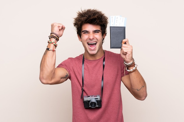 Young caucasian man over isolated wall happy in vacation with passport and plane tickets