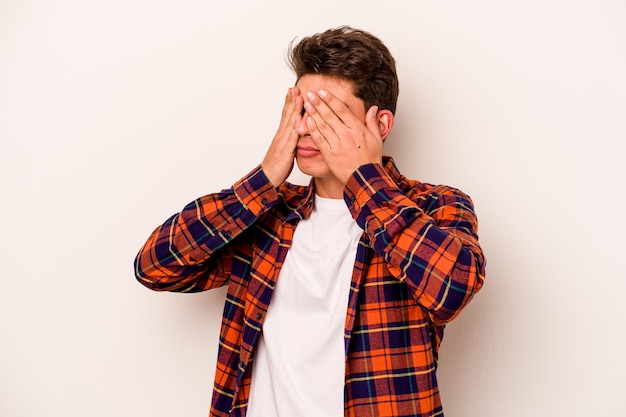 Young caucasian man isolated on white background afraid covering eyes with hands