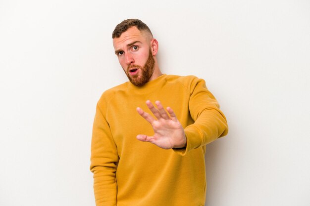 Young caucasian man isolated on white background being shocked due to an imminent danger