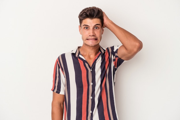 Young caucasian man isolated on white background being shocked, she has remembered important meeting.