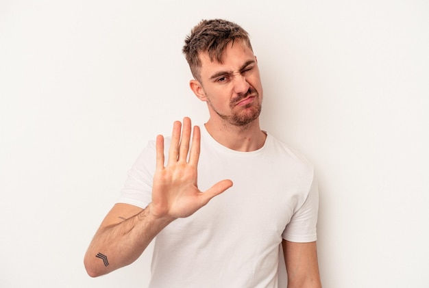 Young caucasian man isolated on white background being shocked, she has remembered important meeting.