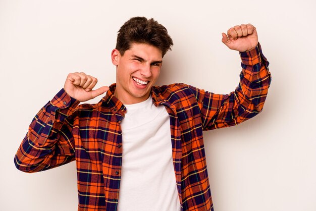 Foto il giovane uomo caucasico isolato su sfondo bianco che celebra un giorno speciale salta e alza le braccia con energia