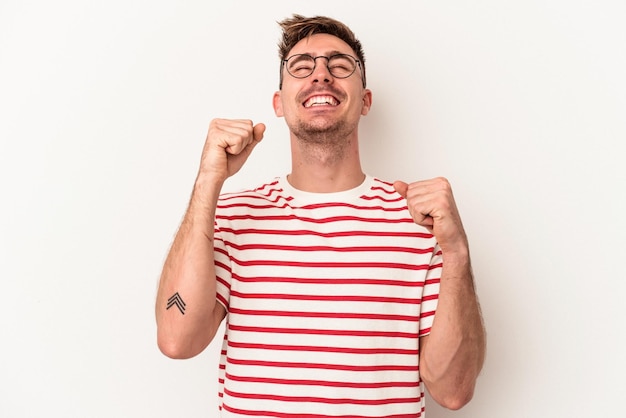 Young caucasian man isolated on white background celebrating a victory, passion and enthusiasm, happy expression.