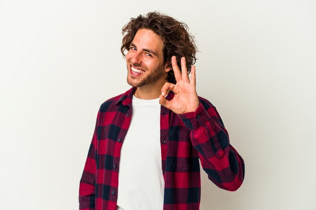 Young caucasian man isolated on white background cheerful and confident showing ok gesture.