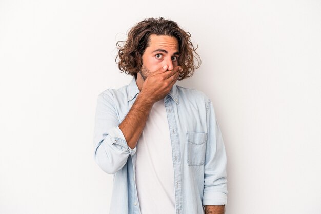 Young caucasian man isolated on white background covering mouth with hands looking worried.