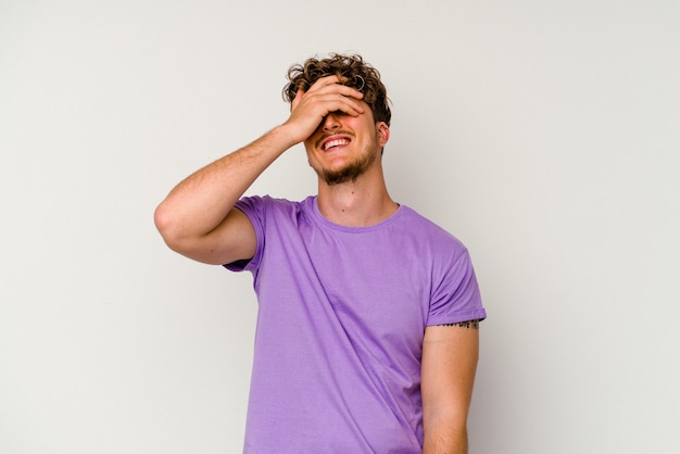 Young caucasian man isolated on white background covers eyes with hands, smiles broadly waiting for a surprise.