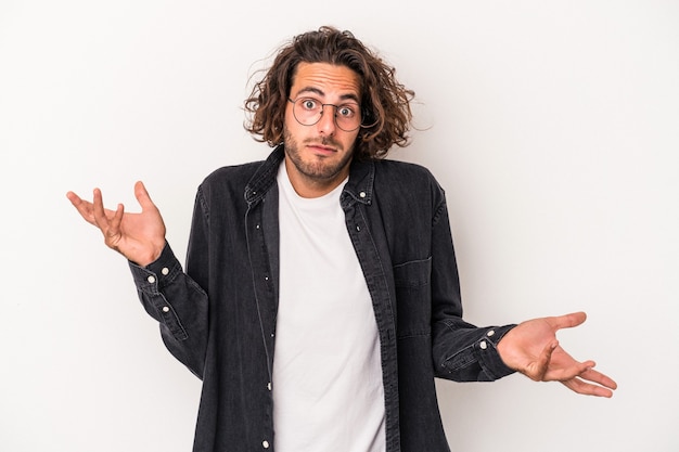 Young caucasian man isolated on white background doubting and shrugging shoulders in questioning gesture.