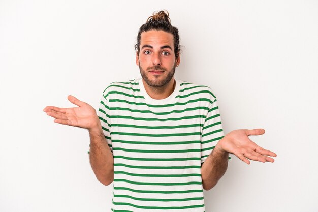 Young caucasian man isolated on white background doubting and shrugging shoulders in questioning gesture.