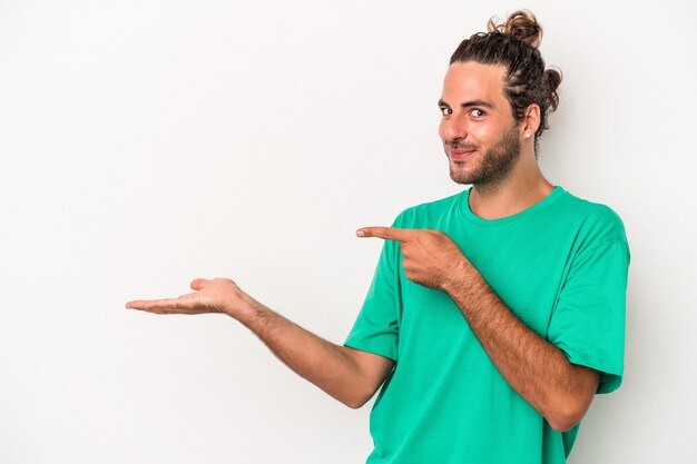 Young caucasian man isolated on white background excited holding a copy space on palm.