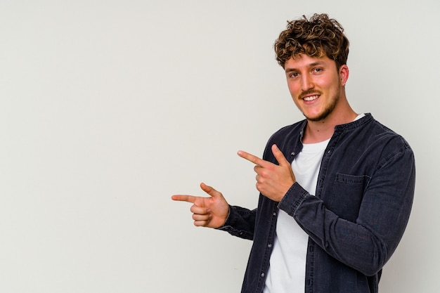 Young caucasian man isolated on white background excited pointing with forefingers away.