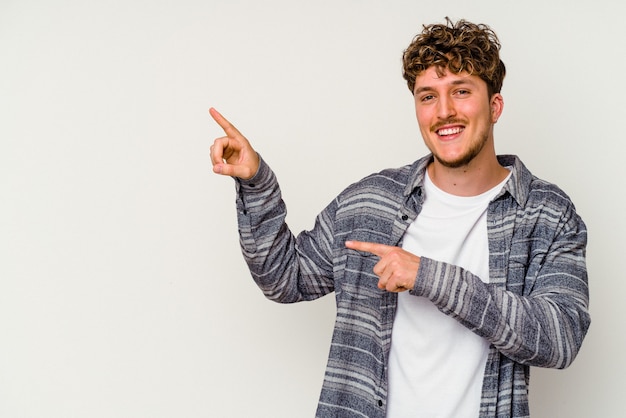 Young caucasian man isolated on white background excited pointing with forefingers away.