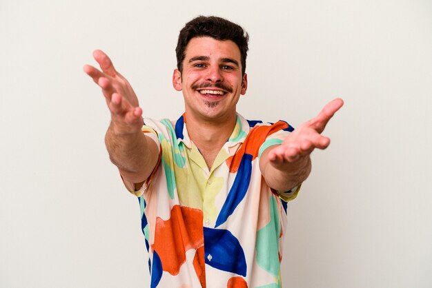 Young caucasian man isolated on white background feels confident giving a hug to the camera.