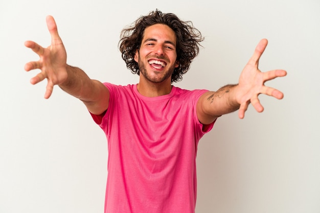 Young caucasian man isolated on white background feels confident giving a hug to the camera.