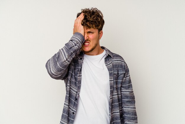 Young caucasian man isolated on white background forgetting something, slapping forehead with palm and closing eyes.