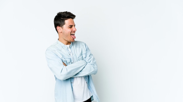 Young caucasian man isolated on white background funny and friendly sticking out tongue.