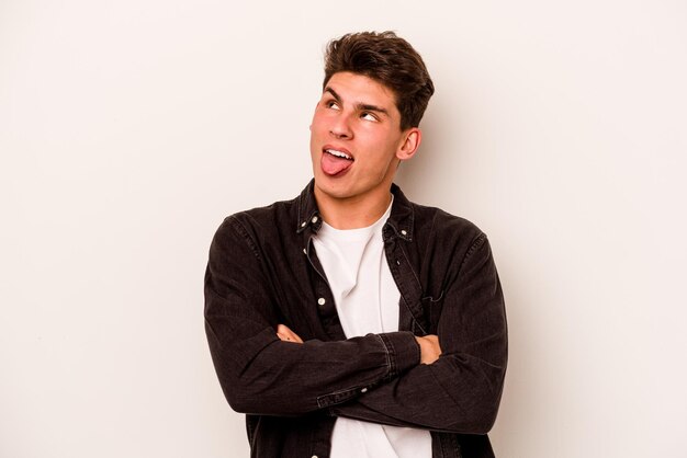 Young caucasian man isolated on white background funny and friendly sticking out tongue