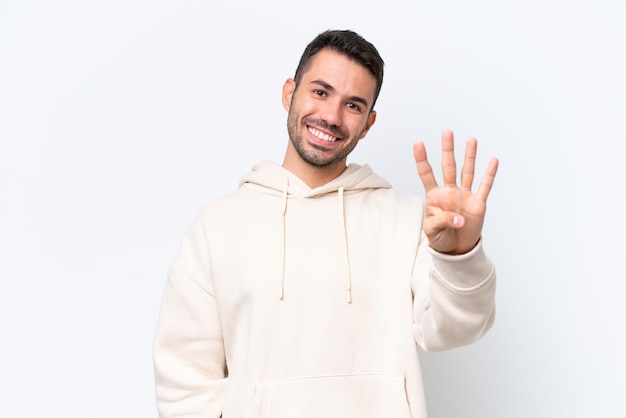 Молодой кавказский мужчина на белом фоне счастлив и считает четыре пальцами