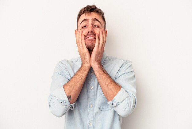 Young caucasian man isolated on white background has friendly expression, pressing palm to chest. Love concept.