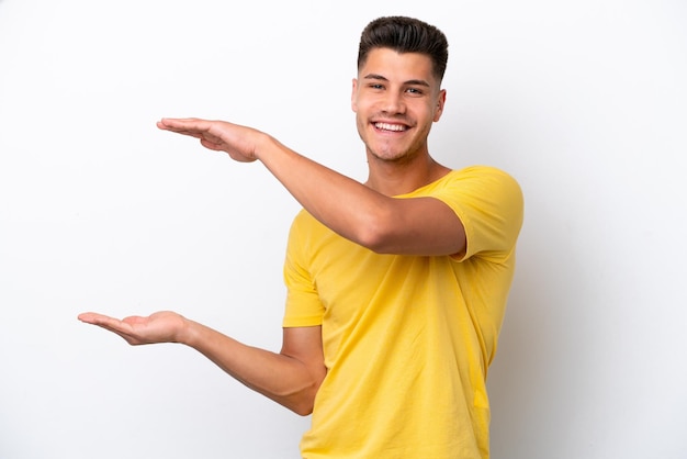 Young caucasian man isolated on white background holding copyspace to insert an ad