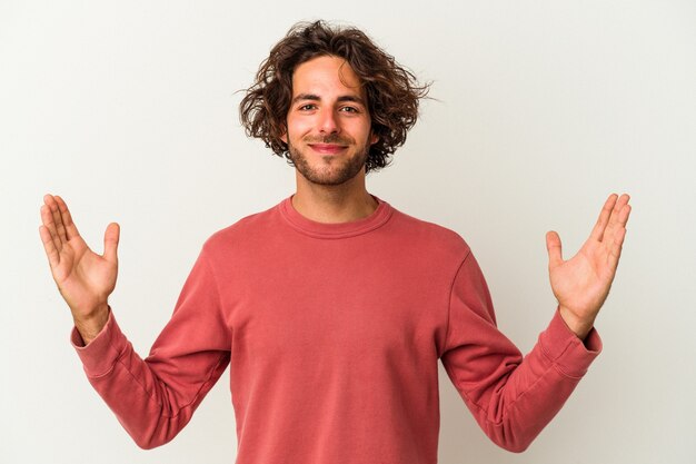 Young caucasian man isolated on white background holding something little with forefingers, smiling and confident.