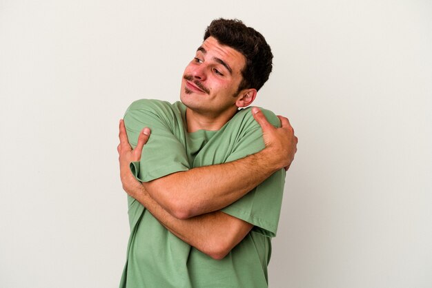 Young caucasian man isolated on white background hugs, smiling carefree and happy.