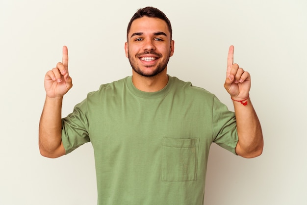 Young caucasian man isolated on white background indicates with both fore fingers up showing a blank space.