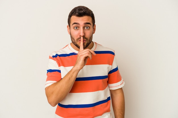 Young caucasian man isolated on white background keeping a secret or asking for silence.