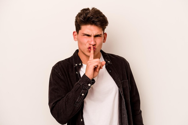 Young caucasian man isolated on white background keeping a secret or asking for silence