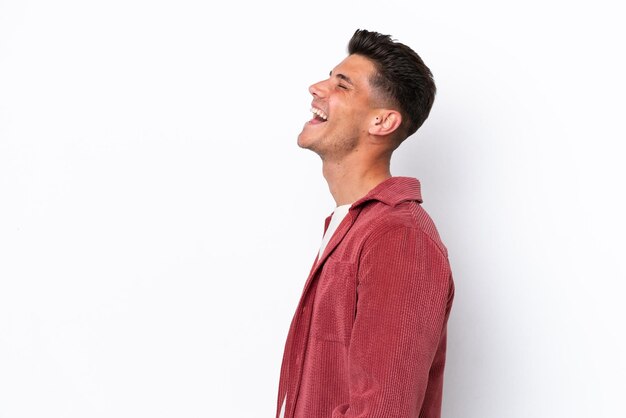 Young caucasian man isolated on white background laughing in lateral position