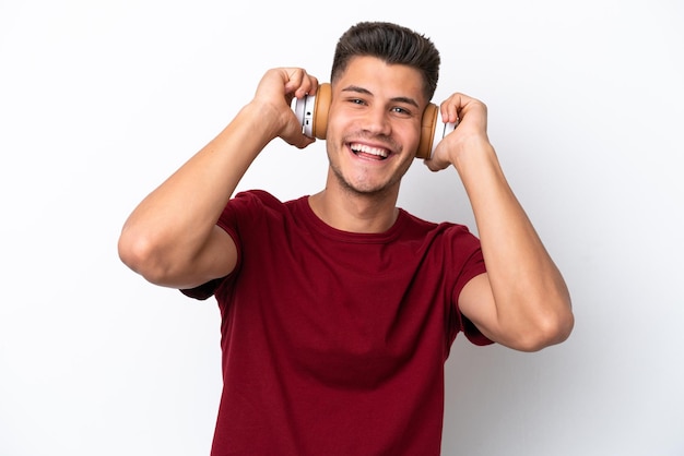 Young caucasian man isolated on white background listening music