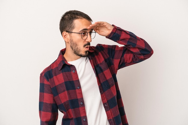 Young caucasian man isolated on white background looking far away keeping hand on forehead.