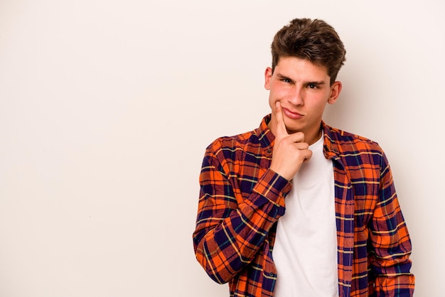 Young caucasian man isolated on white background looking sideways with doubtful and skeptical expression