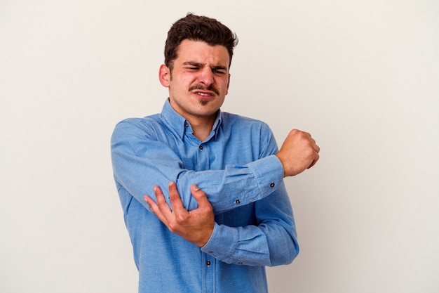 Young caucasian man isolated on white background massaging elbow, suffering after a bad movement.