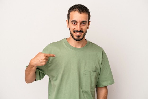 Young caucasian man isolated on white background person pointing by hand to a shirt copy space, proud and confident