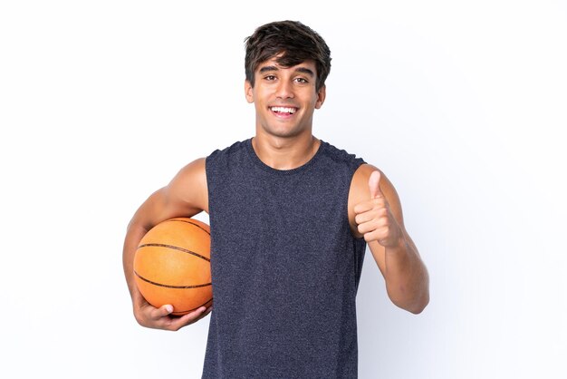 Young caucasian man isolated on white background playing basketball and with thumb up