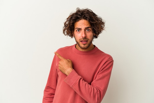 Young caucasian man isolated on white background pointing to the side