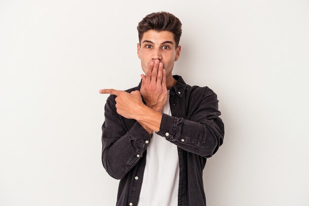 Young caucasian man isolated on white background pointing to the side