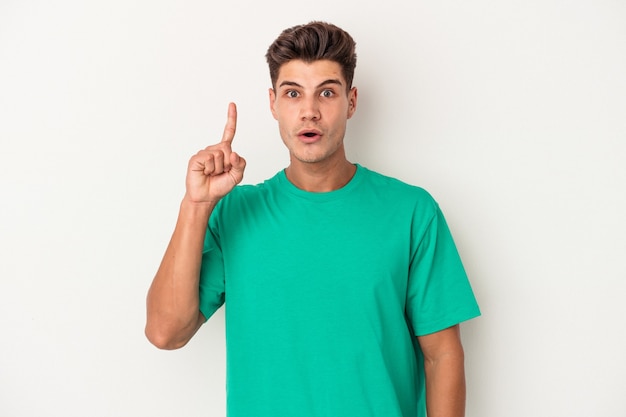 Young caucasian man isolated on white background pointing upside with opened mouth.