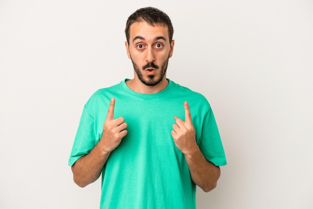 Young caucasian man isolated on white background pointing upside with opened mouth.