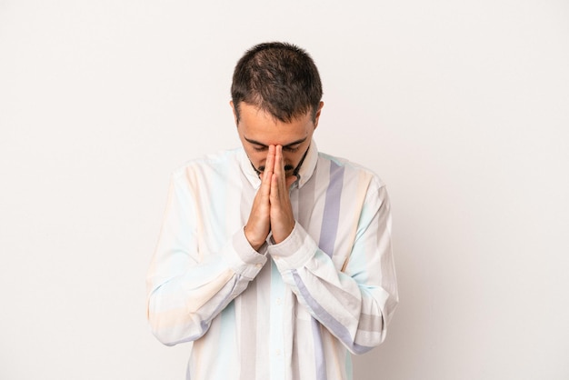 Young caucasian man isolated on white background praying showing devotion religious person looking for divine inspiration