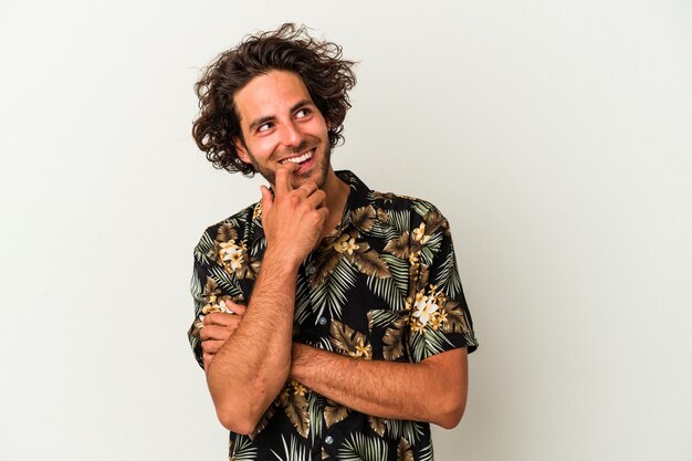 Young caucasian man isolated on white background relaxed thinking about something looking at a copy space.