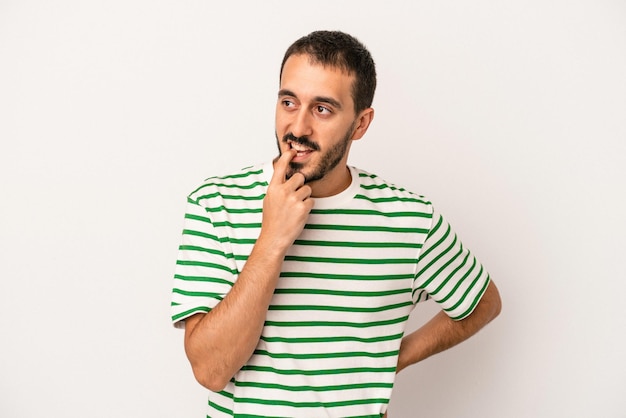 Young caucasian man isolated on white background relaxed thinking about something looking at a copy space