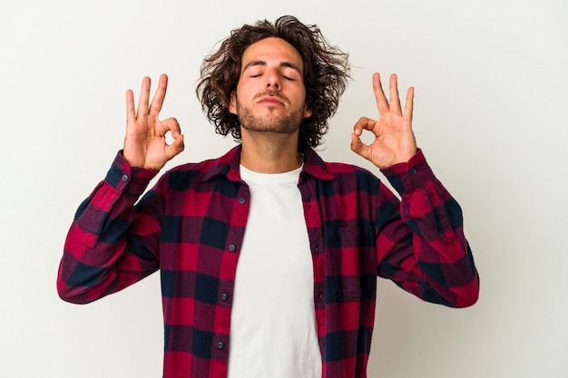 Young caucasian man isolated on white background relaxes after hard working day, she is performing yoga.