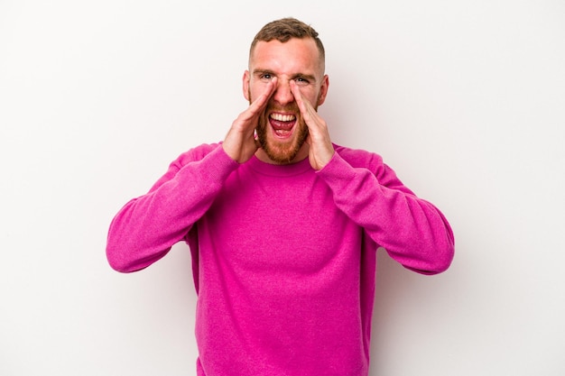 Young caucasian man isolated on white background saying a gossip, pointing to side reporting something.