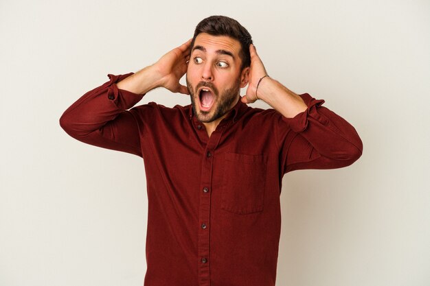 Young caucasian man isolated on white background screaming, very excited, passionate, satisfied with something.